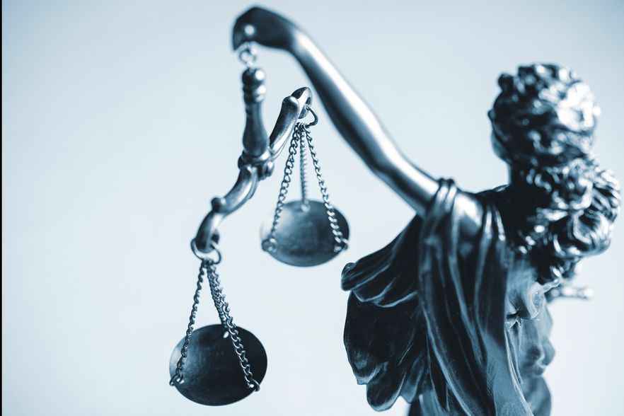 Statue der Gerechtigkeit, die eine Waage hält, symbolisiert das Streben nach Fairness und Gleichgewicht in der Rechtsprechung.